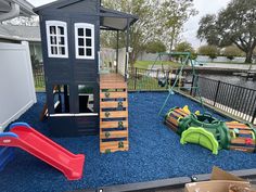 there is a play area in the back yard with blue gravel and wooden steps leading up to it