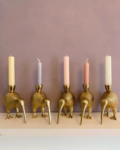 gold elephant candlesticks lined up in a row on a shelf against a purple wall