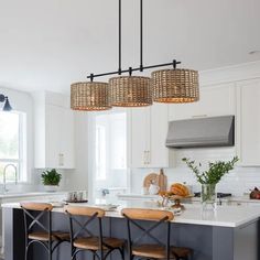 a kitchen island with stools and lights hanging from it's ceiling over the counter