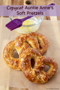 three soft pretzels sitting on top of a table next to a bowl of dip