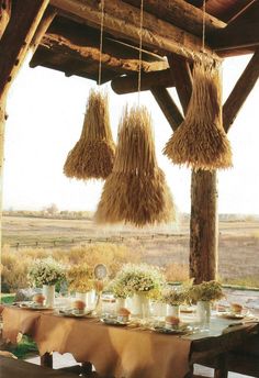 an open book with straw hanging from it's ceiling and flowers on the table