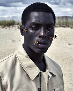 a man with black skin and gold nose piercings on his face in the desert