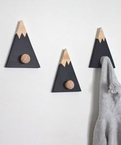 three pieces of wood are hanging on the wall, and one piece is holding a pair of gloves