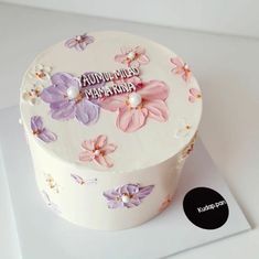 a white cake with pink and purple flowers on it