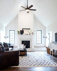 a living room with white walls and ceiling fan