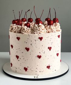 a cake with white frosting and red hearts on it