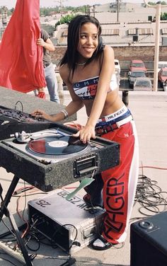 a woman in red pants standing next to a dj's turntable