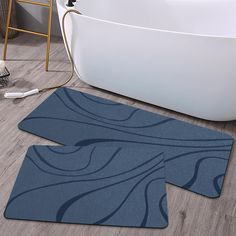 two bathroom rugs on the floor in front of a bathtub