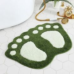 a green and white rug with paw prints on the floor next to a bathtub