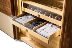 an open wooden cabinet with drawers and clothes in it's bottom drawer, showing the inside compartments