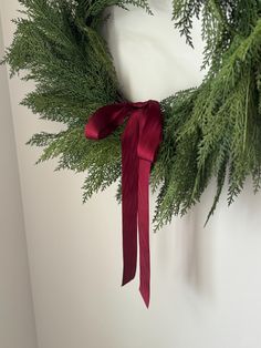 a wreath with red ribbon hanging on the wall