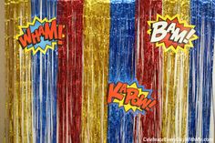 the curtain is decorated with red, yellow and blue tinsels that spell out boom