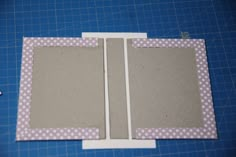 an open photo album sitting on top of a blue cutting mat next to a pair of scissors