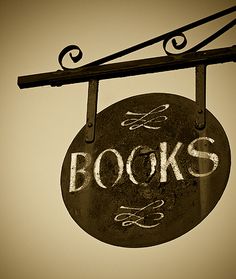 a sign that reads books and is hanging from the side of a building with an iron bar