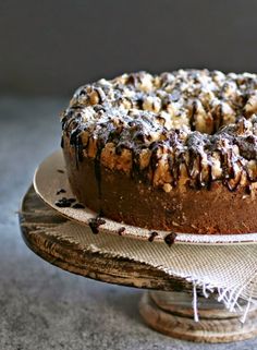 a chocolate cake with nuts and icing on a wooden platter, ready to be eaten