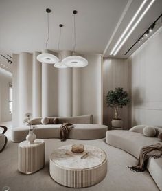 an elegant living room with white walls and beige couches, round coffee table and lamps