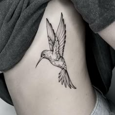 a bird tattoo on the back of a woman's stomach