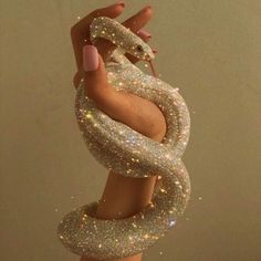 a woman's hand holding onto a large snake like object with glitter on it