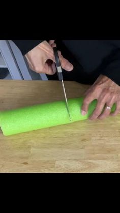 a person cutting up a piece of neon green material with a pair of scissors on top of it