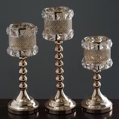 three crystal candlesticks sitting on top of a table