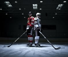 two hockey players standing on the ice with their sticks in front of them and wearing jerseys