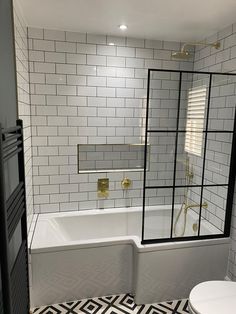 a white bathroom with black and white tile on the floor, shower, toilet and bathtub