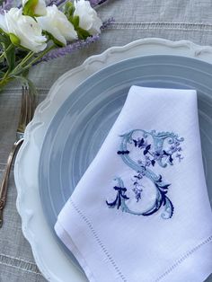 a plate with a napkin on it next to some flowers and a silverware holder