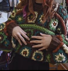 a woman is wearing a crocheted sweater and holding her hands on her hip