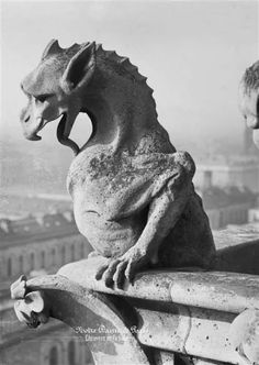 a gargoyle sitting on top of a building with its mouth open and it's tongue out