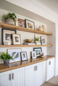 a shelf with some pictures on it and other items in the shelves above them that are open