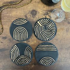 three black and white coasters sitting on top of a wooden table next to a bottle of wine