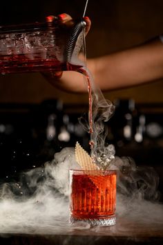 a person pouring something into a glass filled with liquid