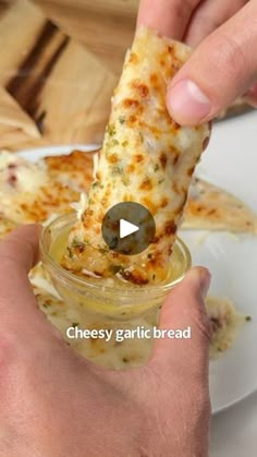 a person holding a piece of pizza in their hand and dipping it into a jar