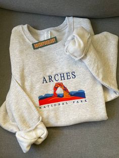 - Arches National Park Embroidered Hoodie - Perfect gift for nature lovers, adventurers, or anyone who loves National Parks.  - Fabrication - Heathered grey color crewneck - 70/20 cotton/poly blend - Size is unisex - Care Instructions - Turn inside out and machine wash cold on delicate cycle - Dry on low heat setting - Do not bleach or dry clean - Processing and Shipping Times - Please allow 3-5 business days for your order to be processed and stitched - Standard shipping takes 3-5 days - Please Cute Embroidered Sweatshirt, National Park Sweatshirt Outfit, Outdoor Crew Sweatshirt With Graphic Print, Outdoor Graphic Print Crew Neck Sweatshirt, National Park Hoodie, National Parks Sweatshirt, Yosemite Sweatshirt, State Embroidery, Camping Clothes