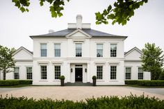 a large white house surrounded by hedges and trees