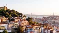 an aerial view of a city with lots of buildings on the hillside and a bridge in the background