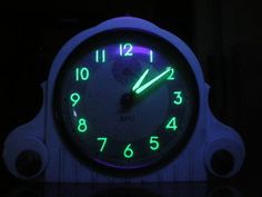 a clock that is lit up in the dark with green numbers on it's face