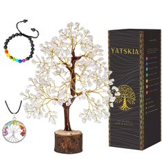 a tree with white flowers is next to a box and some beads are around it