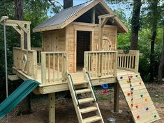 a wooden play house with stairs and slide