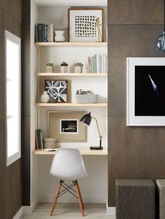 a white chair sitting in front of a wooden shelf filled with books and other items