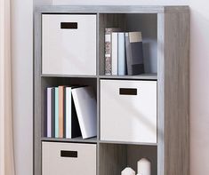 a book shelf with several bins on top of it and books in the bottom