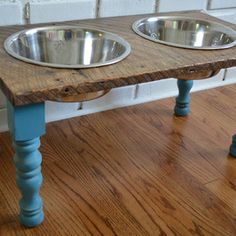 two metal bowls sitting on top of a wooden table in front of a brick wall