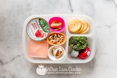 a plastic container filled with food on top of a marble countertop next to an apple