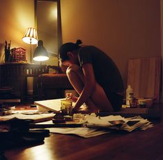 a woman sitting on the floor in front of a table with papers and other items