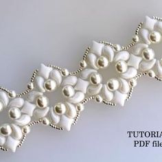 a close up of a white ribbon with pearls on it's end and beading around the edge