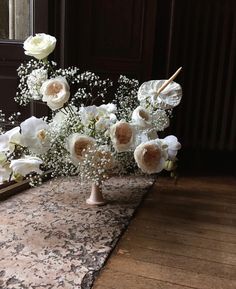 a bouquet of white flowers sitting on top of a wooden table next to a mirror