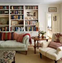 a living room filled with furniture and bookshelves covered in lots of bookcases