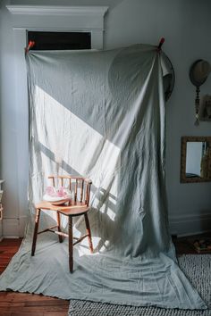 a chair sitting on top of a wooden floor next to a white tarp covered wall