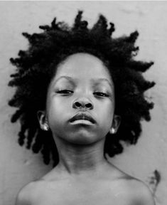 a black and white photo of a child with dreadlocks