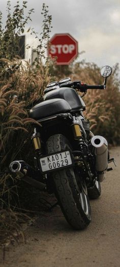 a black motorcycle parked on the side of a road next to a red stop sign